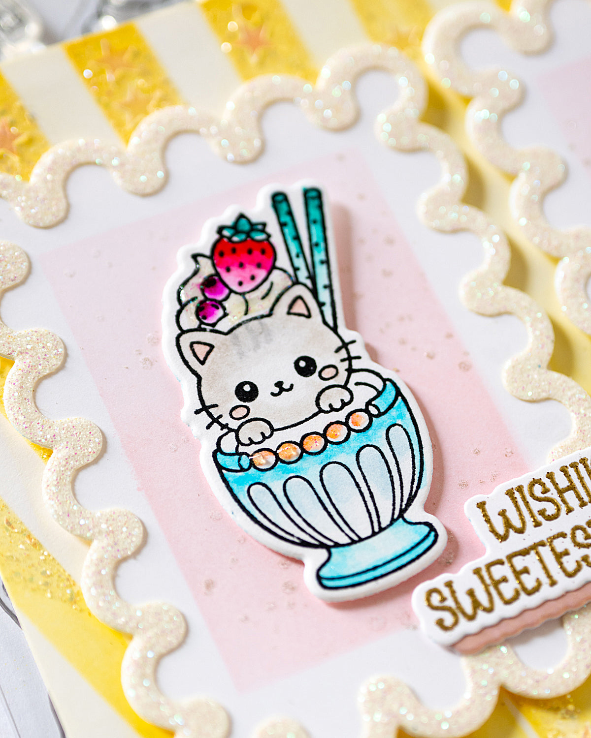 A close-up of a handmade greeting card featuring a cute white kitten in a blue milkshake with a strawberry on top, surrounded by scalloped glittery borders - Sweet treats alex syberia designs stamp