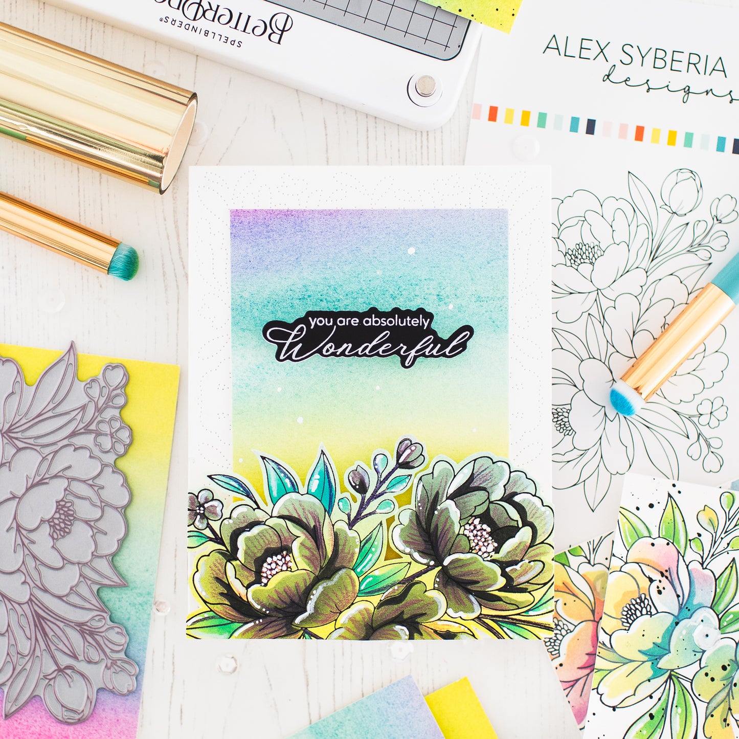 Coloring book with floral design and 'you are absolutely wonderful' text, surrounded by coloring supplies.alex-syberia-designs-lush-peony-pressplate-cardmaking in the uk-cardmaking supplies-best