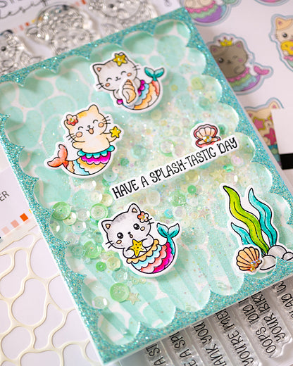 A close-up of a handmade layered card featuring a scalloped aqua glitter base, clear bubble inserts, and cute mermaid cat stickers with colorful tails and starfish accents. 'HAVE A SPLASH-TASTIC DAY' Alex Syberia Designs Mermaid-kittes stamp- kawai or coloring